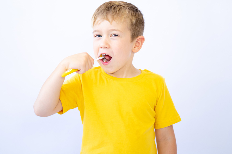kolorowe wypełnienia w zębach mlecznych chłopiec szczotkujący zęby