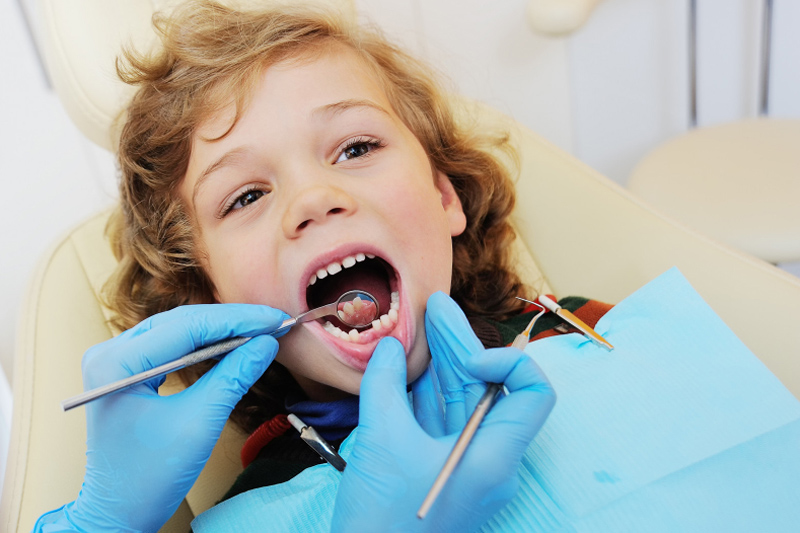 lakowanie zębów u dzieci uśmiechnięta chłopak w gabinecie